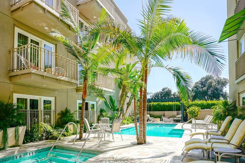 Tropical resort courtyard with palm trees, lounge chairs, and turquoise swimming pools