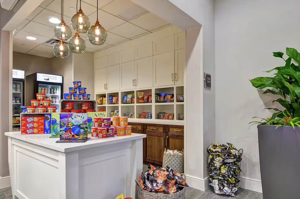 Modern candy shop interior with white cabinetry, shelving, pendant lights, and colorful snack displays on counter