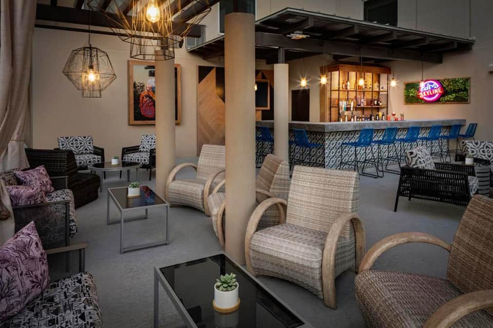Modern resort lounge with patterned chairs, geometric pendant lights, and a blue-accented bar in the background