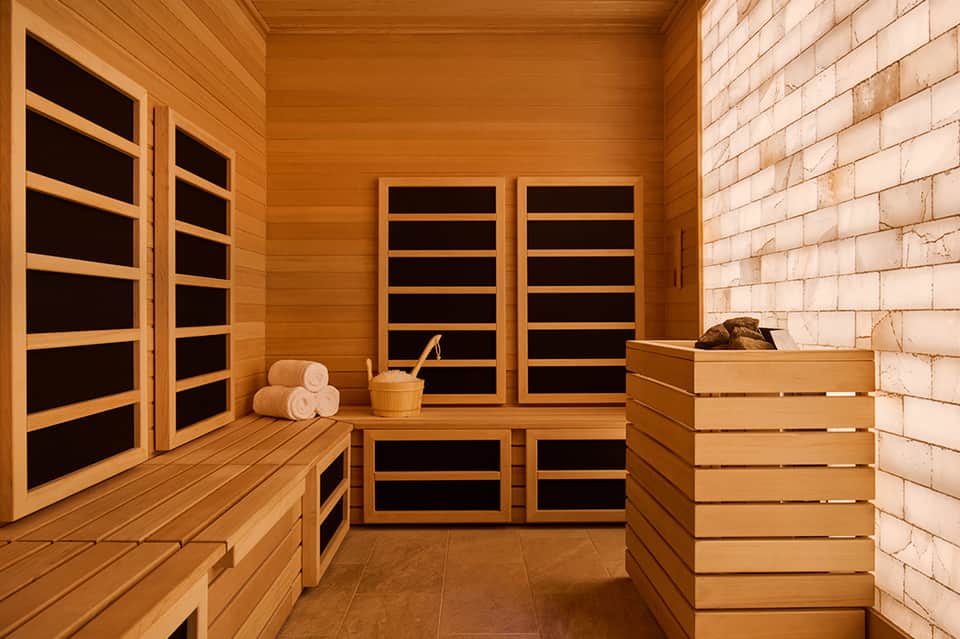 Infrared sauna interior with wooden walls, benches, and heating panels on doors and walls