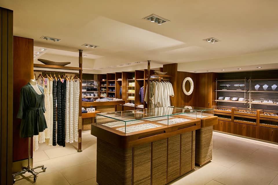Upscale boutique retail shop with clothing racks, wooden display cases, and jewelry showcases