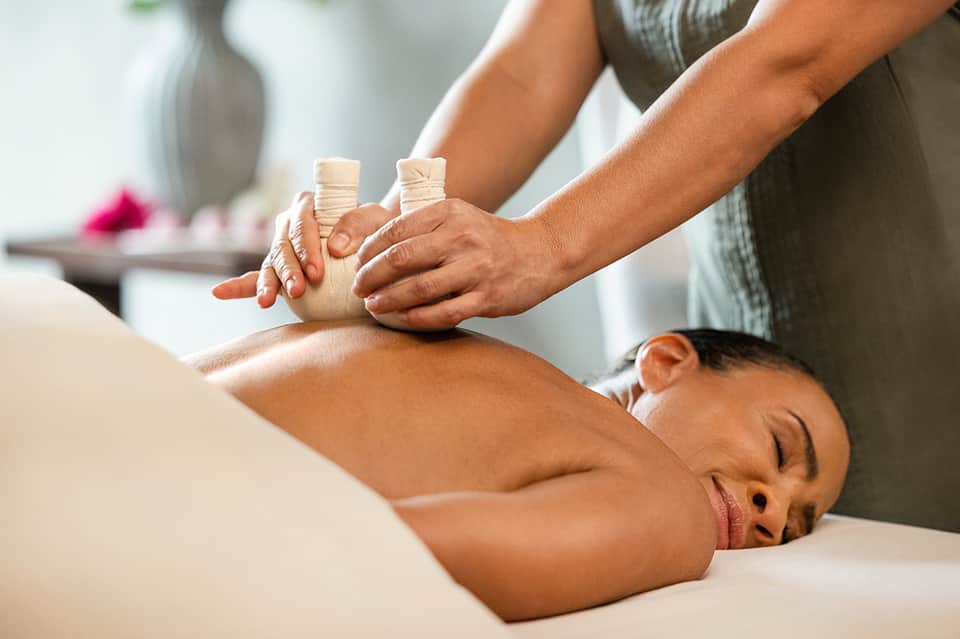 Therapist performing massage on relaxed client with wrapped hands in spa setting