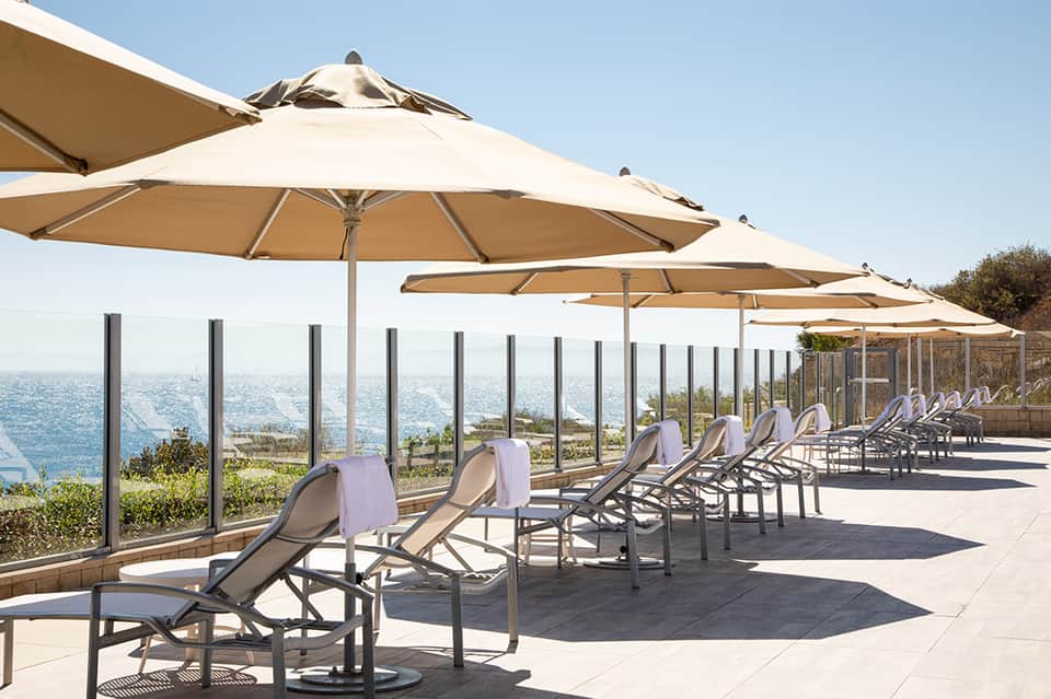 Oceanfront terrace with tan umbrellas and loungers overlooking the sea