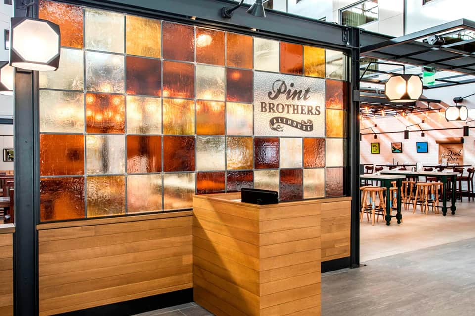 Pint Brothers Alehouse entrance with colorful glass tile wall and wooden reception desk