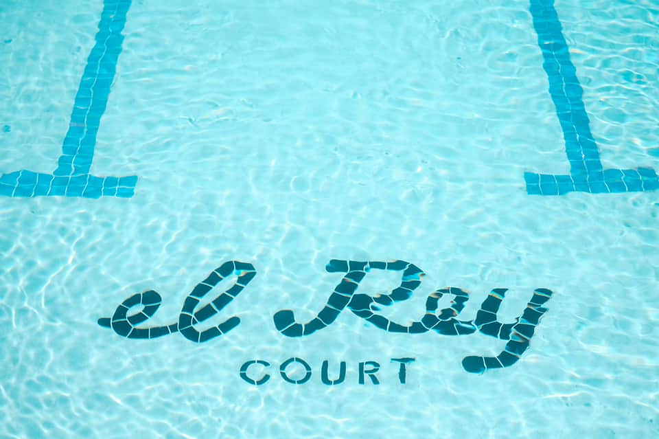 Le Parc Court pool bottom text visible in clear turquoise water with lane dividers