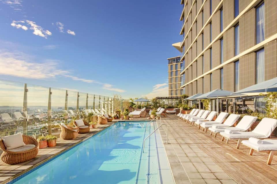 Rooftop infinity pool with city skyline views, lounge chairs, and modern high-rise hotel building