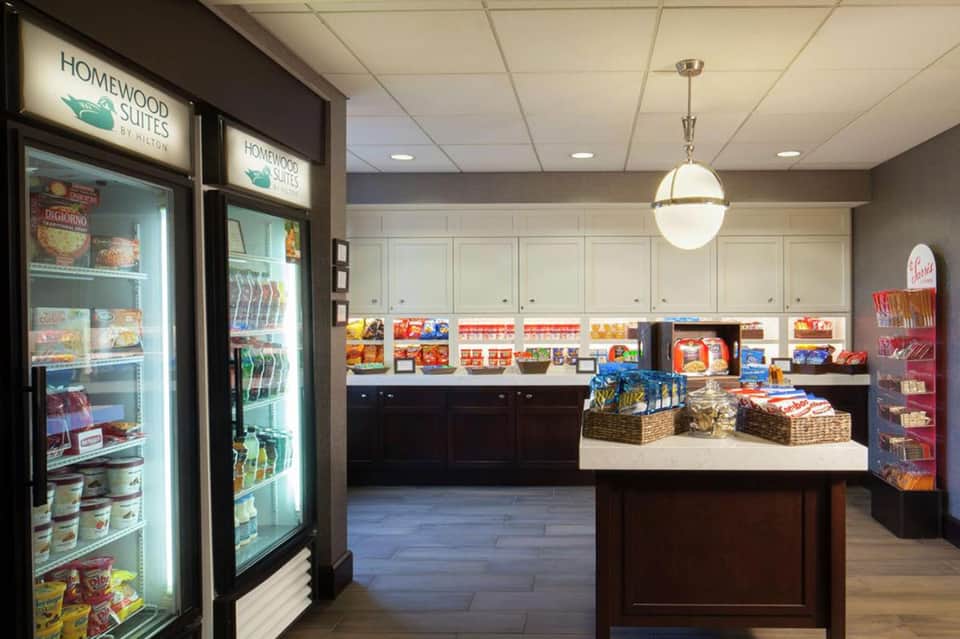 Homewood Suites lobby with refrigerated grab-and-go market, snack baskets, and white cabinetry
