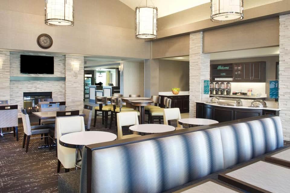 Contemporary hotel lobby with fireplace, seating areas, pendant lighting, and modern furniture in neutral tones