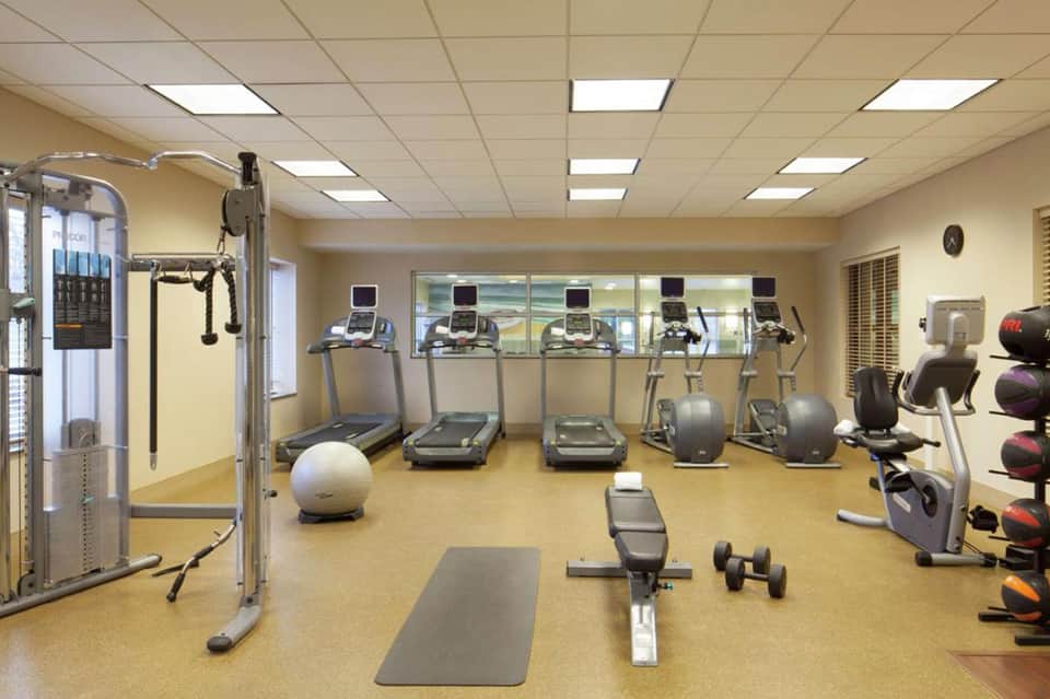 Modern fitness center with treadmills, exercise bikes, weight machines, dumbbells, and gym equipment