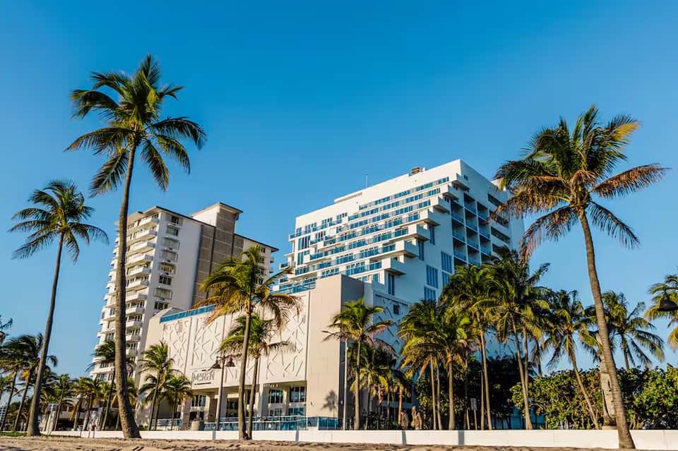 Beachfront hotel buildings with palm trees under clear blue sky
