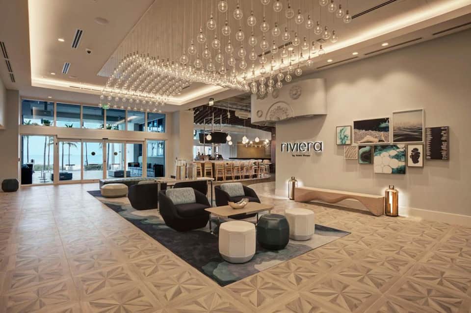 Modern hotel lobby with elegant crystal pendant lighting, contemporary seating, and floor-to-ceiling windows overlooking outdoor views