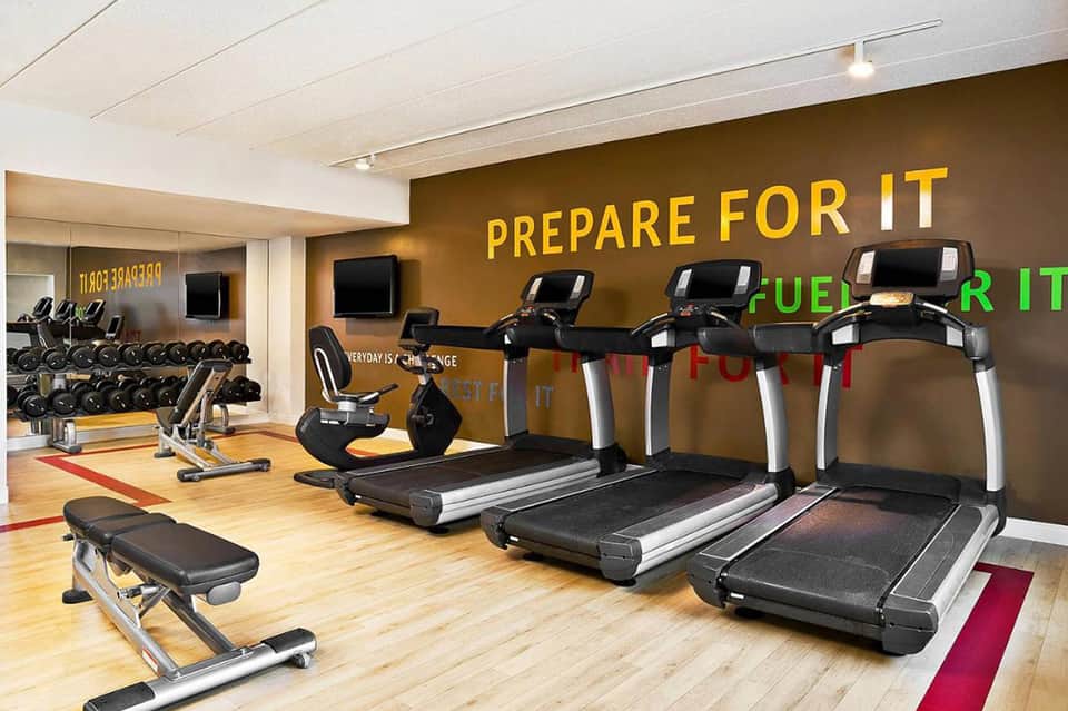 Modern fitness center with treadmills, exercise bikes, dumbbells, and motivational wall signage