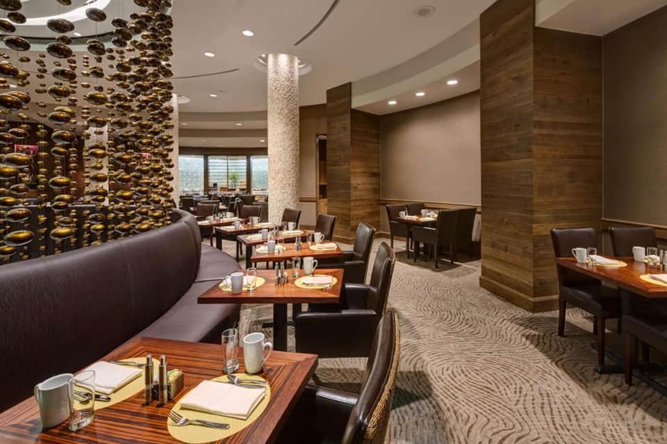 Upscale restaurant dining room with decorative gold ceiling panels, wood accents, and contemporary seating