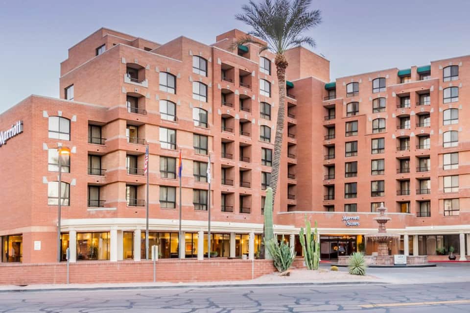 Marriott hotel exterior with red brick facade, multiple stories, ground floor retail, and palm tree