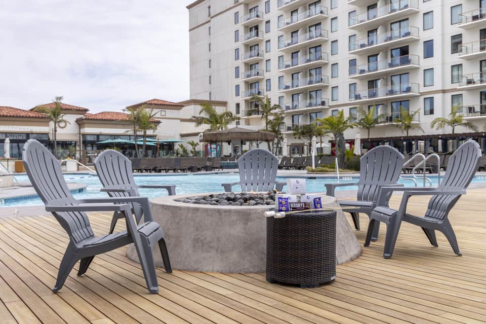 Resort fire pit lounge with gray Adirondack chairs and pool in background