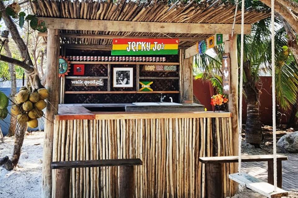 Jerky Jo's beachside shack with corrugated metal counter and colorful flag decorations