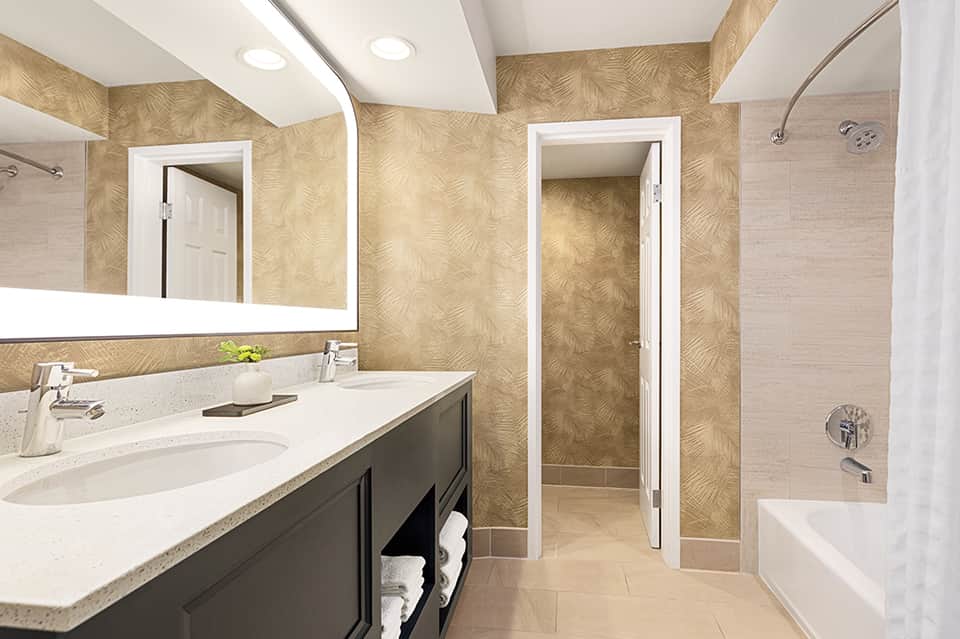 Luxury bathroom with large mirror, vanity sink, and walk-in shower with tan tile walls