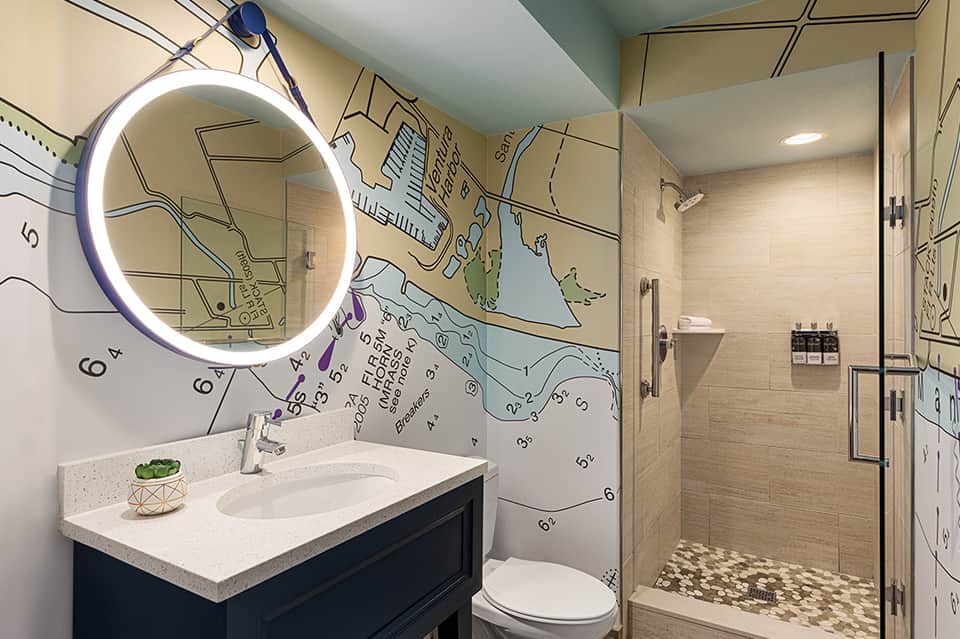 Modern bathroom with neon ring mirror, white sink vanity, map wall mural, and walk-in shower