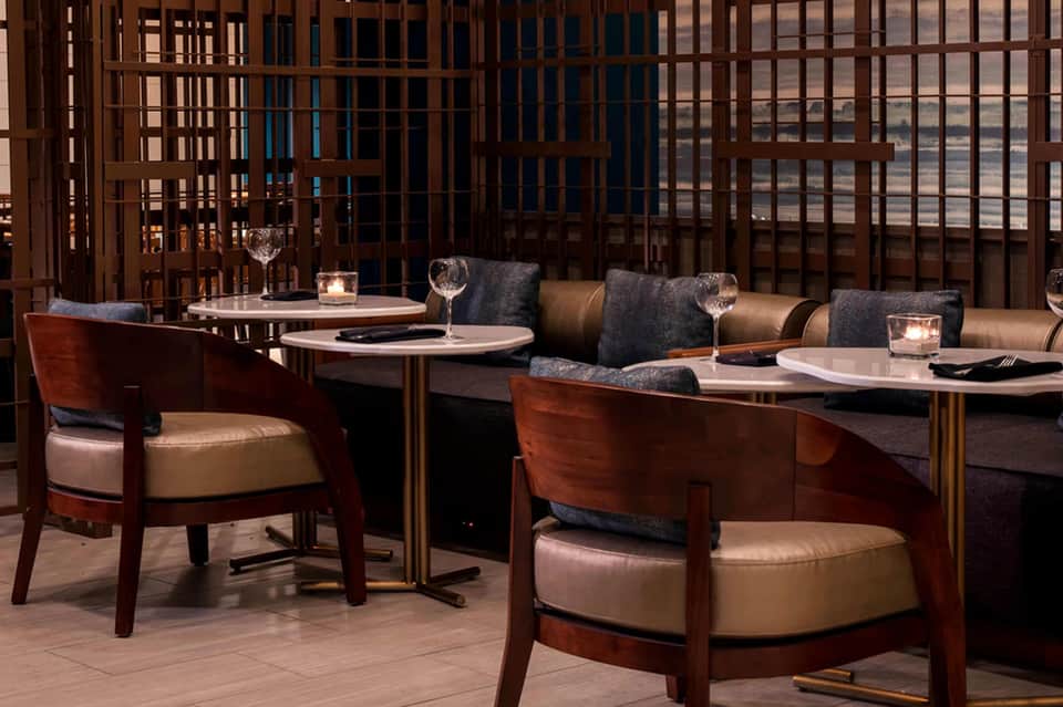 Upscale dining area with wooden chairs, leather seating, and decorative lattice screens overlooking city views