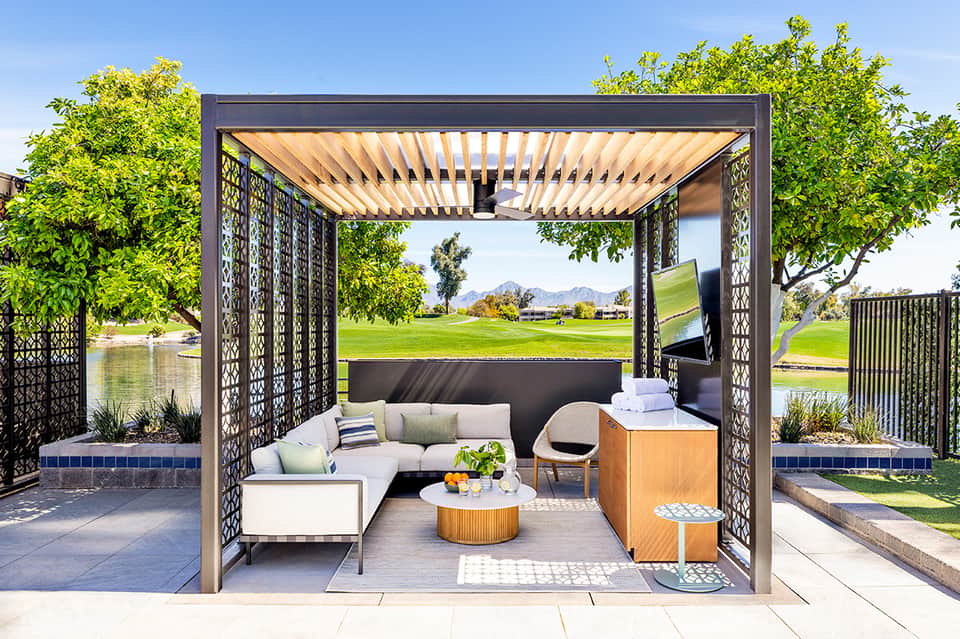 Outdoor pergola lounge with cream seating, coffee table, and golf course views with mountains
