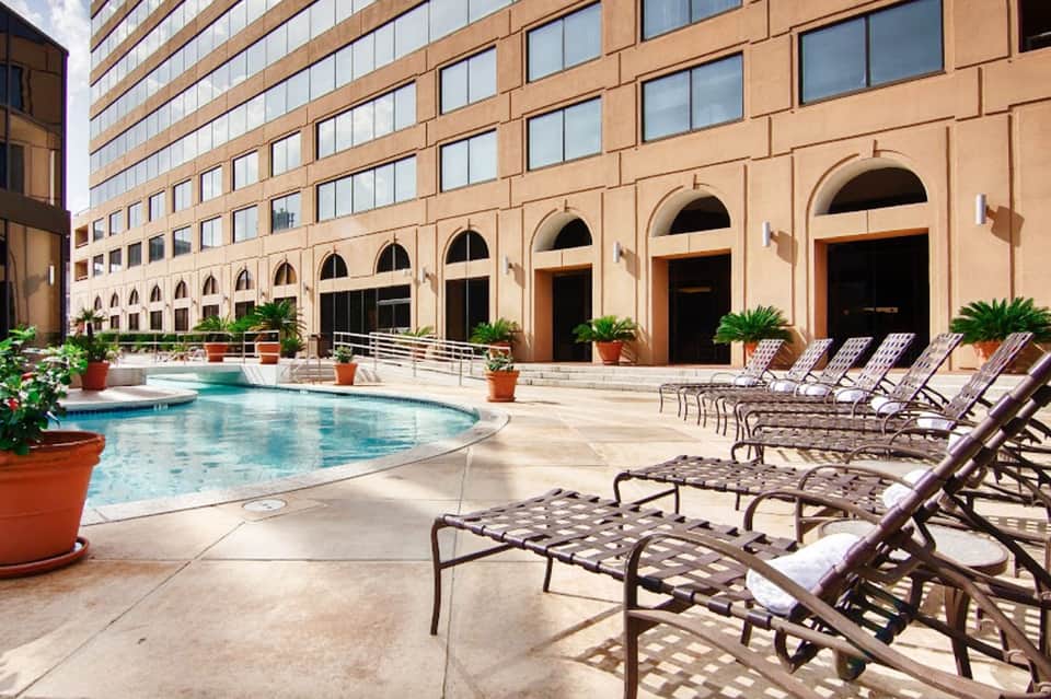Resort courtyard with arched architecture, lounge chairs, and turquoise pool
