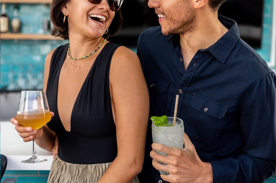 Two guests enjoying cocktails at a poolside bar with turquoise tile backdrop