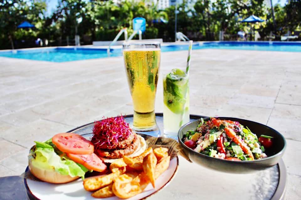 Poolside lunch spread with hamburgers, salad, and refreshing beverages by resort swimming pool