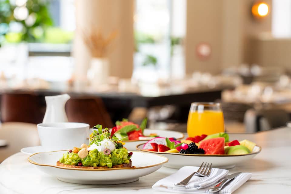 Plated gourmet salad with fresh fruits and orange juice on dining table