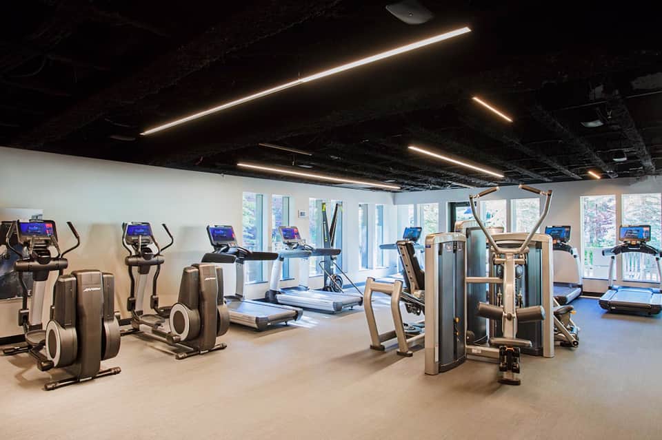 State-of-the-art fitness center with cardio equipment, weight machines, large windows, and modern lighting
