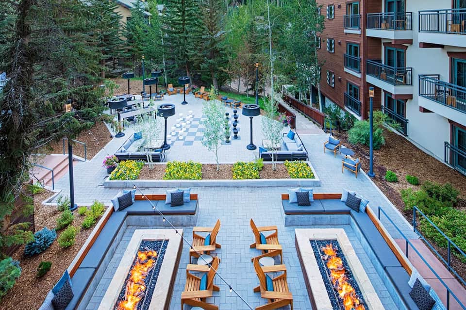 Resort courtyard with fire pits, lounge seating, checkerboard patio, and surrounding residential buildings