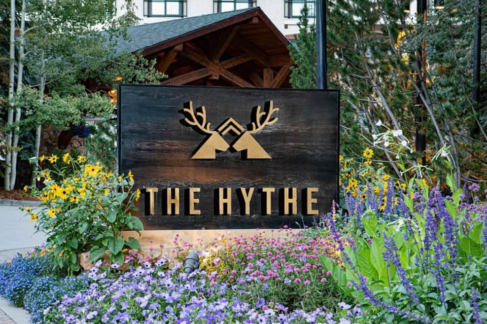 The Hythe resort entrance sign with deer logo surrounded by purple and yellow flowering plants