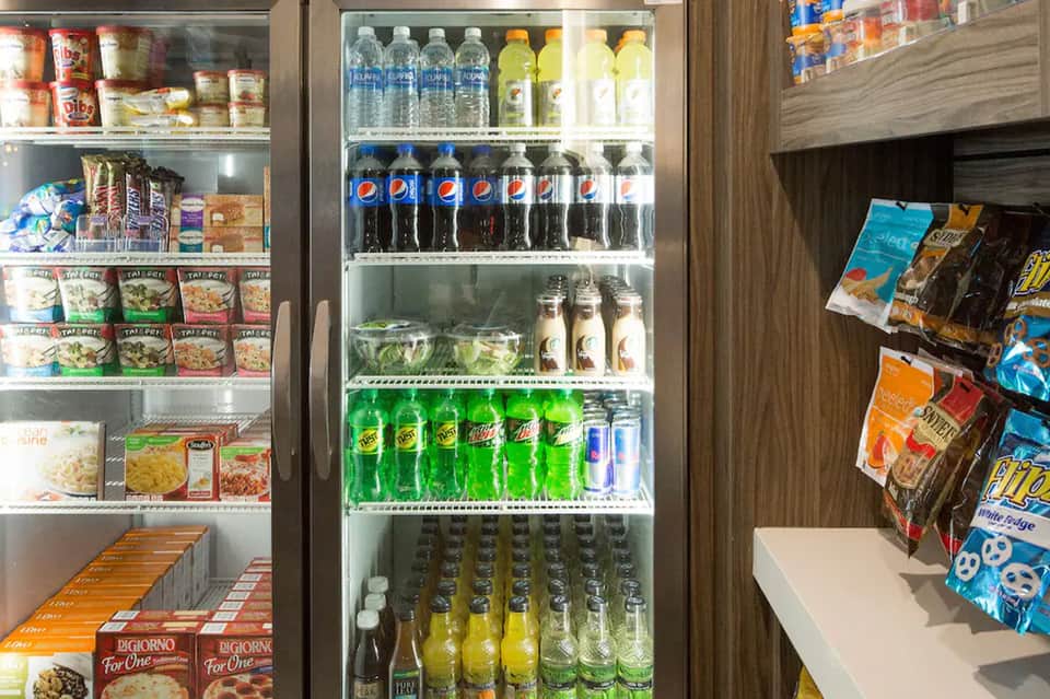 Convenience store refrigerator stocked with beverages, snacks, and packaged food items