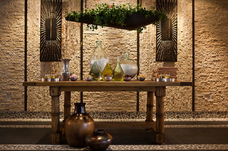 Elegant spa display with stone walls, decorative vessels, potted plants, and ornamental metal screens