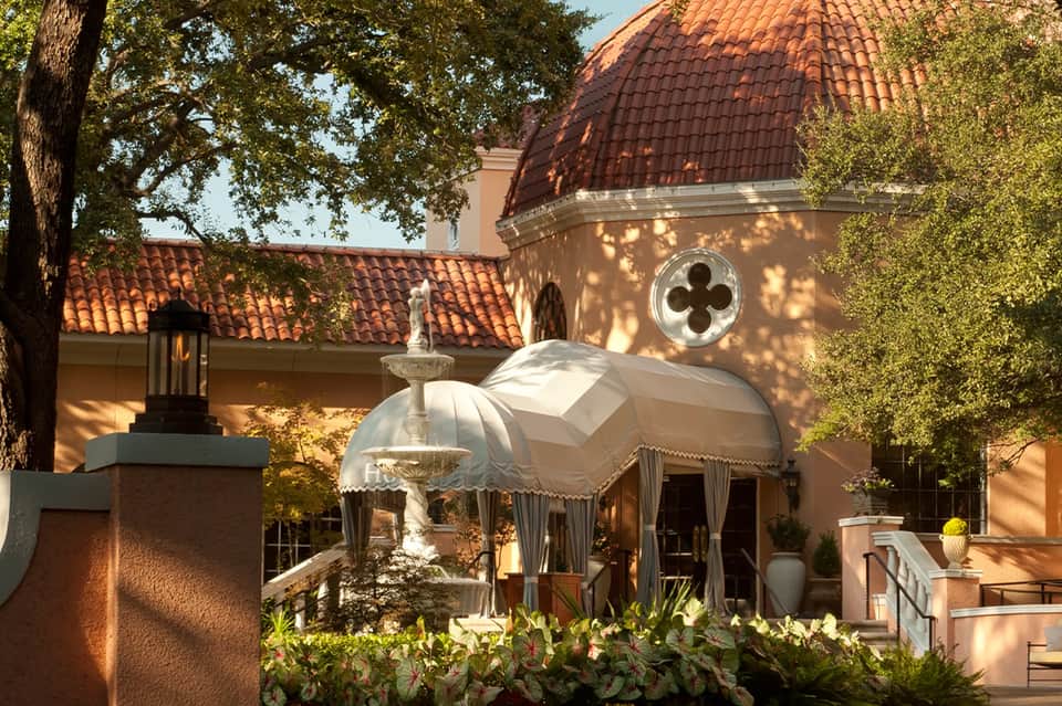 Spanish mission-style building with terra cotta roof, dome, fountain, and manicured gardens