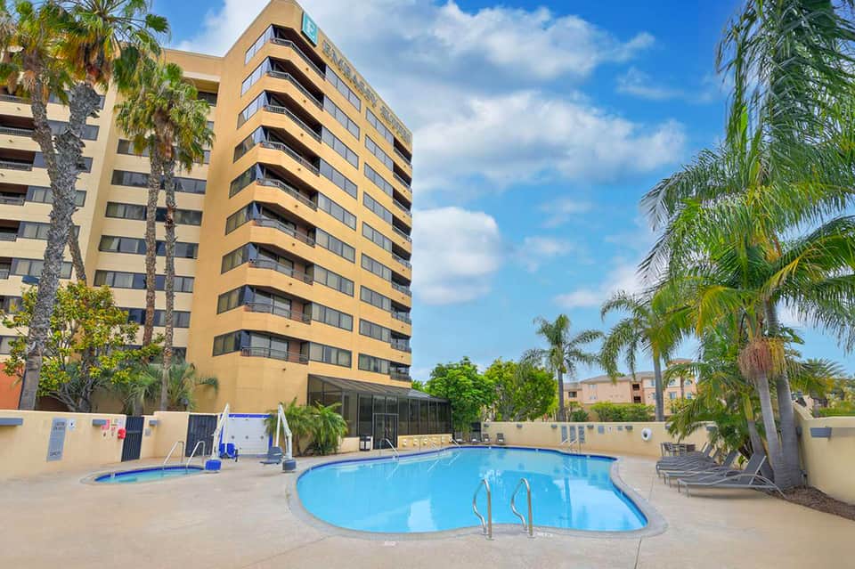 Yellow apartment building with kidney-shaped pool and lounge chairs in courtyard