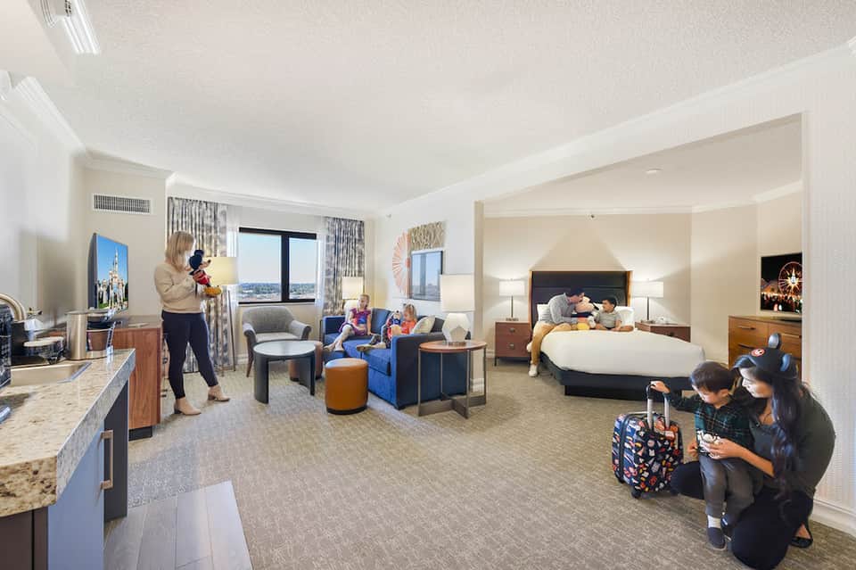 Spacious hotel suite with living area, multiple beds, and families enjoying the accommodations with city views