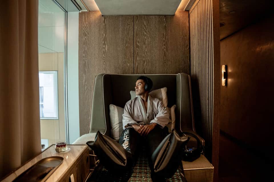 Man relaxing in modern alcove seating nook with wood paneling and ambient lighting