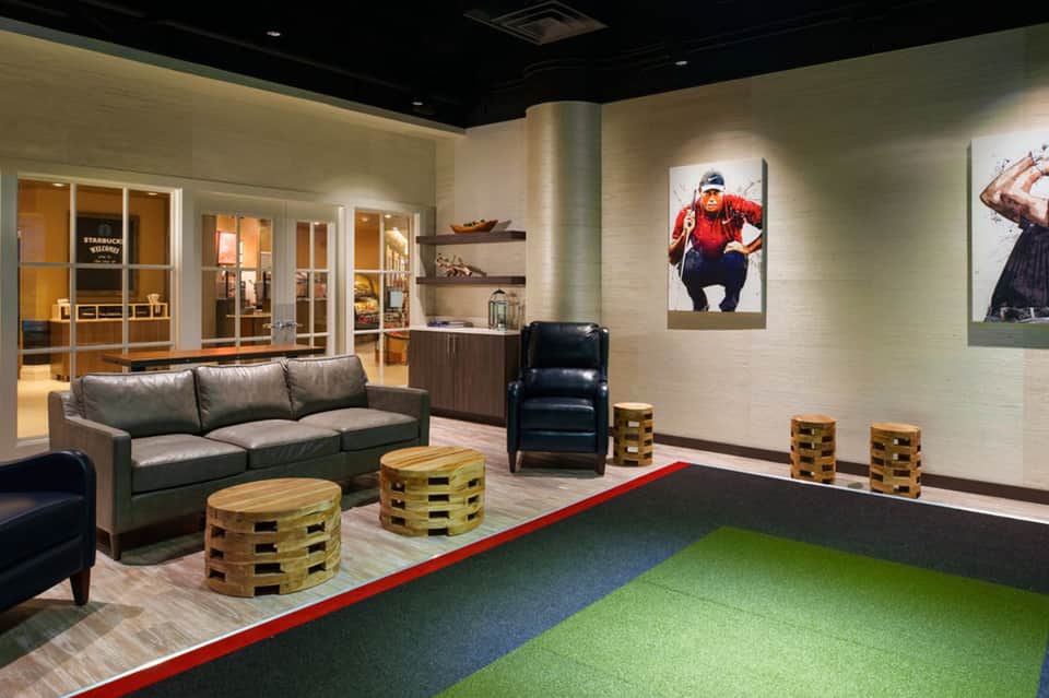 Contemporary recreation lounge with putting green, leather seating, and sports artwork
