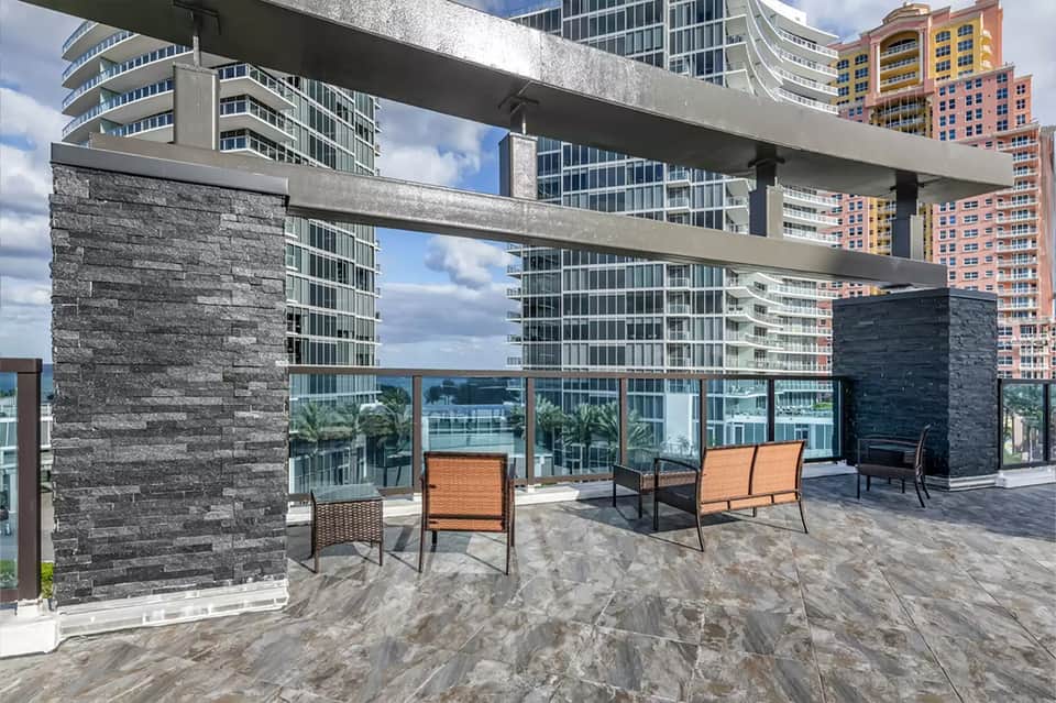 Modern rooftop terrace with stone columns, lounge seating, and downtown skyline views