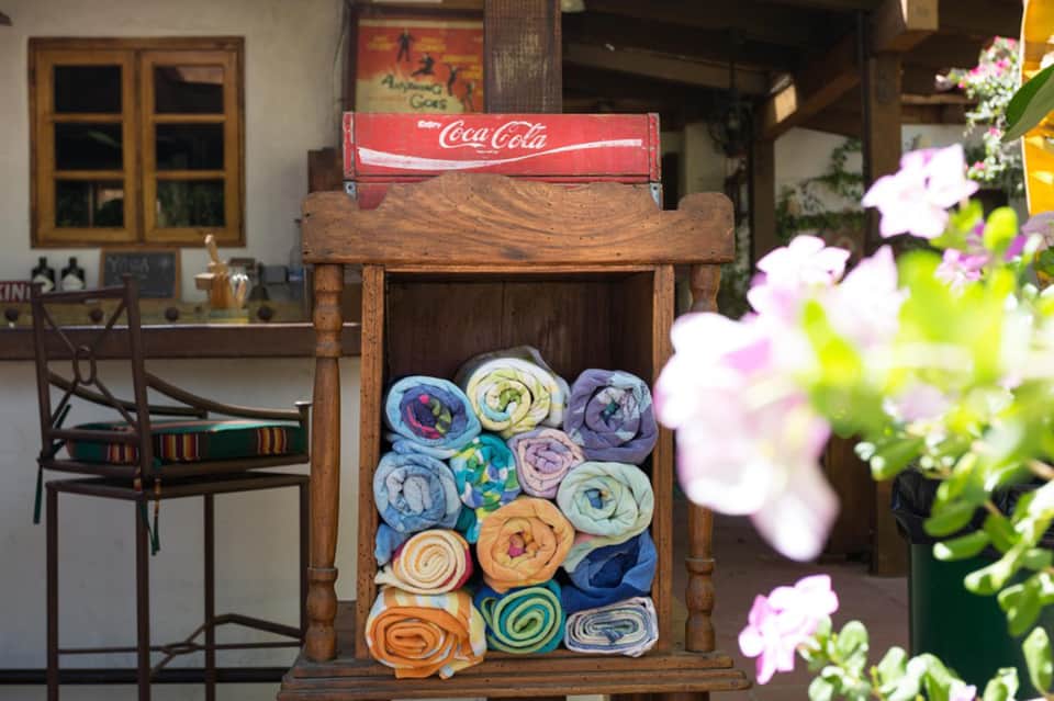 Wooden towel display with rolled colorful towels and Coca-Cola sign in courtyard setting