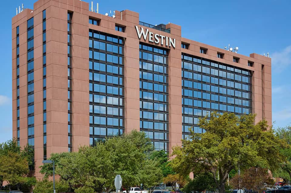 Exterior of The Westin hotel, a multi-story brick building with large windows and signage