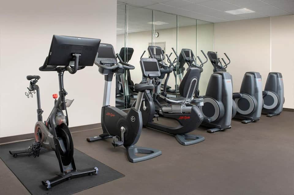 Indoor fitness studio with stationary bikes and elliptical machines equipped with digital displays