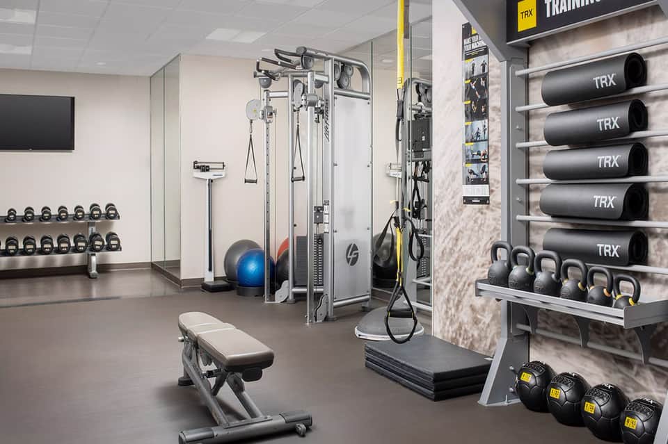 Modern fitness center with TRX training equipment, dumbbells, and cable machines