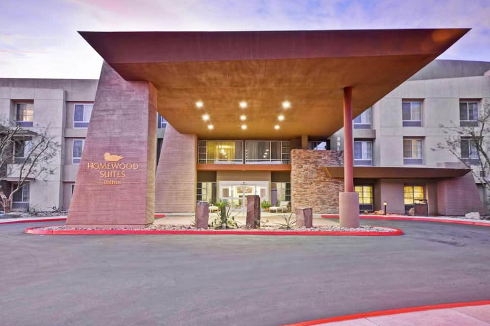 Homewood Suites Hilton entrance with modern canopy, brick and stone facade, illuminated at dusk