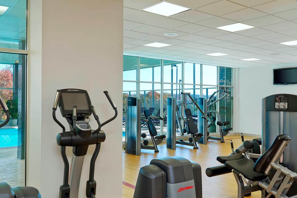 Modern fitness center with elliptical machines, weights, and ocean views through floor-to-ceiling windows