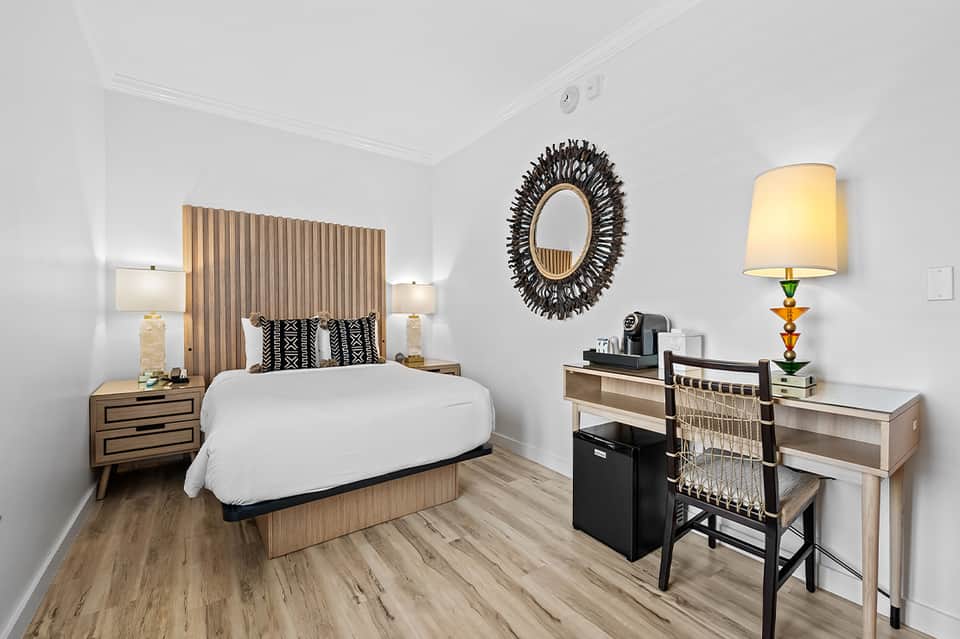 Modern hotel bedroom with wood accent headboard, desk, and contemporary furnishings