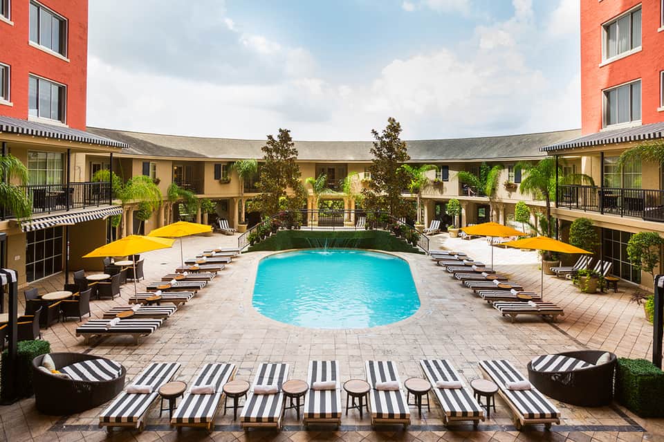 Courtyard pool with yellow umbrellas, striped lounge chairs, and surrounding hotel buildings