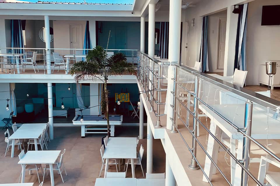 Modern hotel courtyard with multi-level white railings, dining tables, and tropical plants
