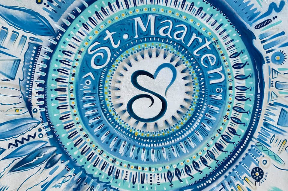 Decorative circular sign with 'St. Maarten' text and heart symbol in blue and turquoise tones