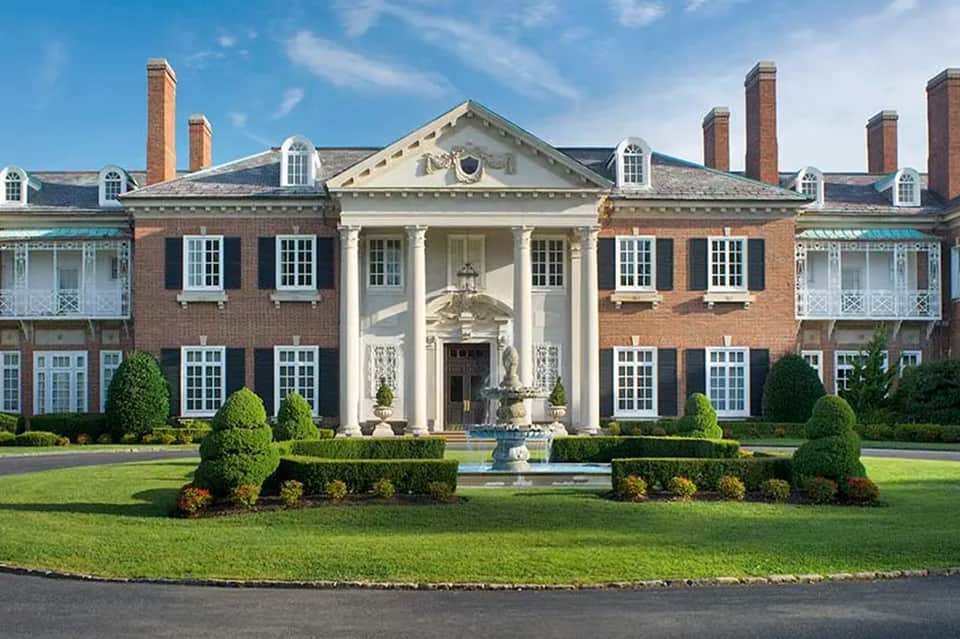 Classical brick mansion with white columns, manicured gardens, and fountain courtyard